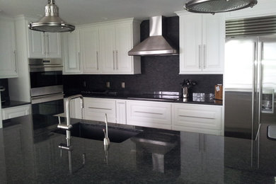 Inspiration for a contemporary u-shaped eat-in kitchen remodel in Milwaukee with a drop-in sink, recessed-panel cabinets, white cabinets, granite countertops, black backsplash, subway tile backsplash, stainless steel appliances and an island