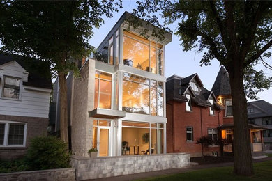 Photo of a mid-sized contemporary two-storey grey house exterior in Ottawa with a flat roof and a metal roof.