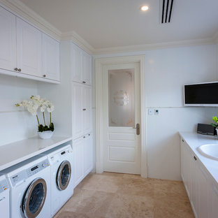 パースの大きいトラディショナルスタイルのおしゃれな家事室 (ドロップインシンク、シェーカースタイル扉のキャビネット、白いキャビネット、白い壁、左右配置の洗濯機・乾燥機、クオーツストーンカウンター、トラバーチンの床) の写真