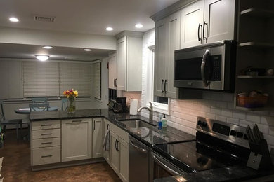 Example of a mid-sized transitional u-shaped ceramic tile and brown floor kitchen design in Baltimore with an undermount sink, shaker cabinets, gray cabinets, granite countertops, white backsplash, subway tile backsplash, stainless steel appliances, no island and black countertops