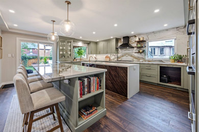 Inspiration for a huge transitional u-shaped vinyl floor and brown floor eat-in kitchen remodel in Toronto with an undermount sink, shaker cabinets, green cabinets, quartz countertops, white backsplash, quartz backsplash, stainless steel appliances, two islands and white countertops