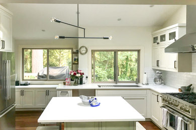 Mid-sized trendy u-shaped medium tone wood floor and brown floor eat-in kitchen photo in Seattle with an undermount sink, shaker cabinets, white cabinets, white backsplash, subway tile backsplash, stainless steel appliances, an island and white countertops