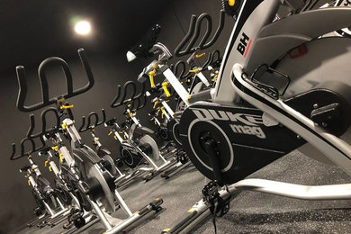 Photo of a large urban home gym in Valencia with black walls, vinyl flooring and black floors.