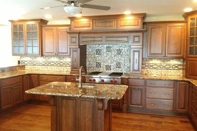 Eat-in kitchen - large traditional u-shaped medium tone wood floor eat-in kitchen idea in Raleigh with an undermount sink, raised-panel cabinets, dark wood cabinets, granite countertops, multicolored backsplash, mosaic tile backsplash, stainless steel appliances and an island