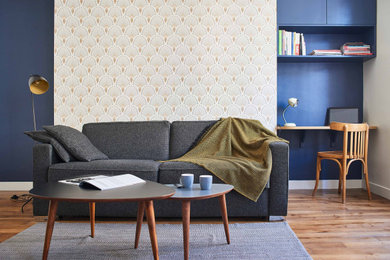 Ejemplo de sala de estar con biblioteca abierta minimalista de tamaño medio sin chimenea con paredes azules, suelo de madera oscura y televisor en una esquina