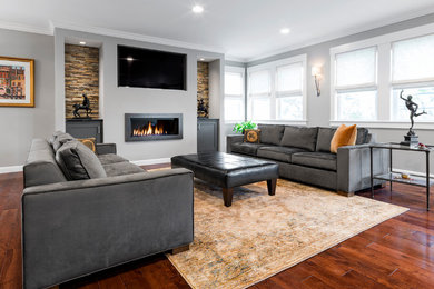 This is an example of a large contemporary open concept living room in Boston with a home bar, grey walls, medium hardwood floors, a ribbon fireplace, a built-in media wall, a metal fireplace surround and brown floor.