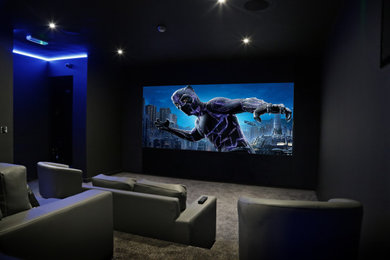 Photo of a modern home cinema in West Midlands with black walls, carpet, a built-in media unit, grey floors and feature lighting.