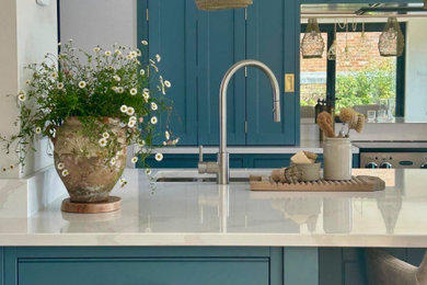 Design ideas for a medium sized classic single-wall kitchen in Surrey with an integrated sink, shaker cabinets, quartz worktops, mirror splashback, stainless steel appliances and an island.