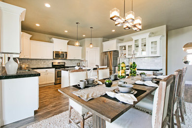 Mid-sized arts and crafts l-shaped medium tone wood floor and brown floor eat-in kitchen photo in Salt Lake City with a double-bowl sink, recessed-panel cabinets, white cabinets, quartz countertops, white backsplash, porcelain backsplash, stainless steel appliances, an island and black countertops