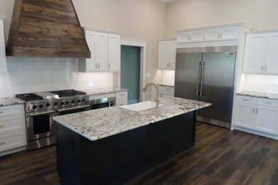 Inspiration for a large country l-shaped dark wood floor, brown floor and vaulted ceiling open concept kitchen remodel in Other with a farmhouse sink, shaker cabinets, white cabinets, quartz countertops, white backsplash, subway tile backsplash, stainless steel appliances, an island and multicolored countertops