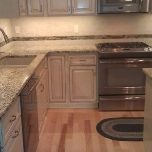 Large traditional kitchen pantry appliance - Kitchen pantry - large traditional l-shaped light wood floor and beige floor kitchen pantry idea in Omaha with an undermount sink, raised-panel cabinets, white cabinets, granite countertops, beige backsplash, porcelain backsplash, stainless steel appliances and an island