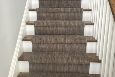 This is an example of a mid-sized transitional wood straight staircase in New York with painted wood risers.
