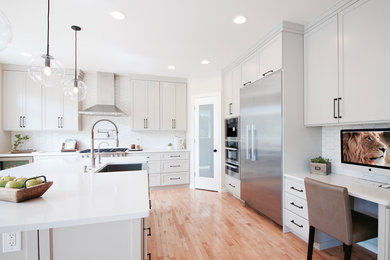 Eat-in kitchen - large transitional l-shaped light wood floor eat-in kitchen idea in Seattle with a farmhouse sink, shaker cabinets, gray cabinets, quartz countertops, white backsplash, porcelain backsplash, stainless steel appliances and an island