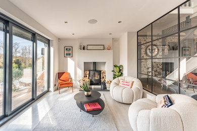 Photo of a contemporary living room in London with white walls, a wood burning stove and beige floors.