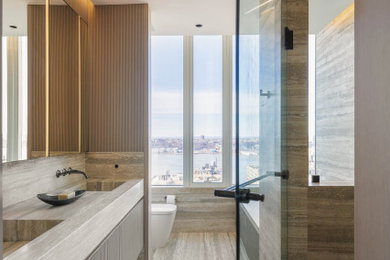 This is an example of a mid-sized contemporary master bathroom in New York with raised-panel cabinets, beige cabinets, a corner tub, an alcove shower, a wall-mount toilet, beige tile, marble, beige walls, marble floors, an integrated sink, marble benchtops, beige floor, a hinged shower door, beige benchtops, a double vanity and a floating vanity.