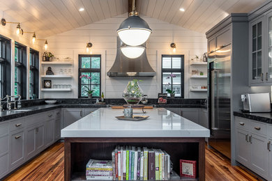 Example of a large beach style u-shaped medium tone wood floor kitchen design in Other with gray cabinets, stainless steel appliances, an island, an undermount sink, shaker cabinets and black countertops
