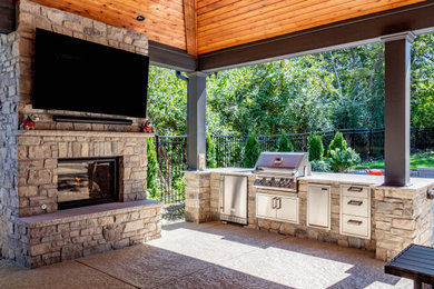 Inspiration for a large backyard concrete patio remodel in St Louis with a fireplace and a roof extension