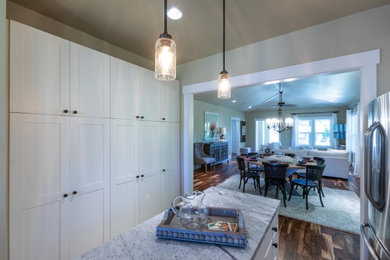 Open concept kitchen - coastal galley dark wood floor, brown floor and vaulted ceiling open concept kitchen idea in Hawaii with shaker cabinets, white cabinets, granite countertops, white backsplash, subway tile backsplash, stainless steel appliances, an island and white countertops
