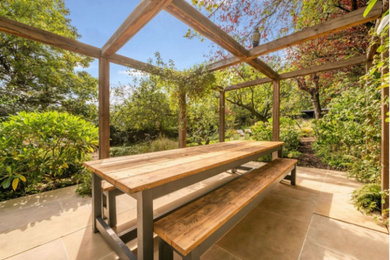 Inspiration for a large country back formal partial sun pergola for spring in London with natural stone paving and a wood fence.