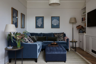 Imagen de salón cerrado clásico con suelo de madera en tonos medios y televisor colgado en la pared
