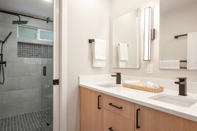 Свежая идея для дизайна: маленькая главная ванная комната в стиле модернизм с плоскими фасадами, светлыми деревянными фасадами, душем без бортиков, раздельным унитазом, серой плиткой, керамогранитной плиткой, белыми стенами, полом из керамогранита, врезной раковиной, столешницей из искусственного кварца, серым полом, душем с раздвижными дверями, белой столешницей, нишей, тумбой под две раковины и встроенной тумбой для на участке и в саду - отличное фото интерьера