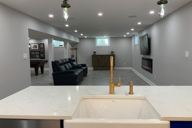 Example of a mid-sized minimalist open concept gray floor game room design in New York with gray walls, a plaster fireplace and a wall-mounted tv