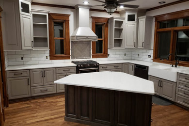 Inspiration for a mid-sized country u-shaped medium tone wood floor and brown floor kitchen pantry remodel in Other with a farmhouse sink, raised-panel cabinets, gray cabinets, quartz countertops, white backsplash, subway tile backsplash, stainless steel appliances, an island and white countertops