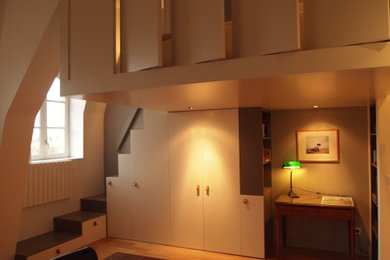 Ejemplo de armario unisex contemporáneo pequeño con armarios con rebordes decorativos, puertas de armario blancas, suelo de madera clara y suelo marrón