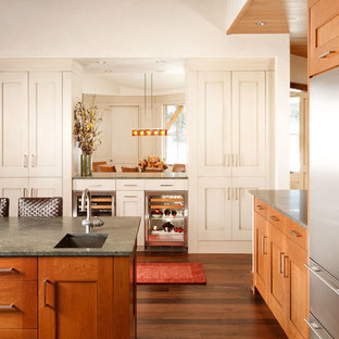 Immagine di una grande cucina classica con elettrodomestici in acciaio inossidabile, lavello sottopiano, ante in stile shaker, top in granito, pavimento in legno massello medio, isola, paraspruzzi beige, paraspruzzi con piastrelle in pietra, ante in legno scuro e pavimento marrone