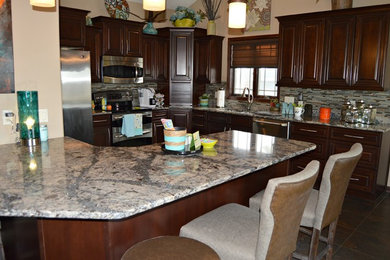 Inspiration for a mid-sized timeless l-shaped ceramic tile eat-in kitchen remodel in Other with a double-bowl sink, raised-panel cabinets, dark wood cabinets, quartzite countertops, multicolored backsplash, glass tile backsplash, stainless steel appliances and an island