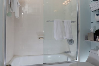 Mid-sized beach style 3/4 gray tile and matchstick tile mosaic tile floor and white floor bathroom photo in Miami with recessed-panel cabinets, white cabinets, a one-piece toilet, blue walls, a vessel sink and laminate countertops
