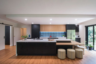Design ideas for a large contemporary galley open plan kitchen in Adelaide with a double-bowl sink, flat-panel cabinets, black cabinets, quartz benchtops, blue splashback, cement tile splashback, stainless steel appliances, laminate floors, with island, brown floor, white benchtop and recessed.