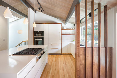 Inspiration for a large contemporary l-shaped light wood floor and brown floor kitchen remodel in Portland with an undermount sink, flat-panel cabinets, white cabinets, quartz countertops, window backsplash, paneled appliances and an island
