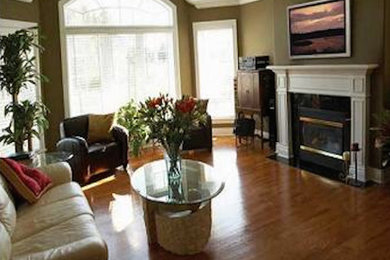 Inspiration for a timeless medium tone wood floor family room remodel in Orlando with green walls, a standard fireplace and a wall-mounted tv
