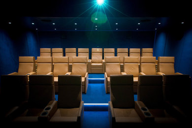 Photo of a large contemporary enclosed home cinema in Cornwall with blue walls, carpet and a projector screen.