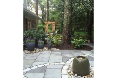 This is an example of a mid-sized craftsman shade backyard stone landscaping in Other for summer.