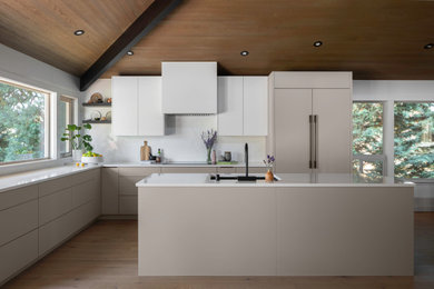1960s light wood floor, beige floor and vaulted ceiling kitchen pantry photo in Seattle with an undermount sink, flat-panel cabinets, beige cabinets, quartz countertops, white backsplash, stone slab backsplash, black appliances, an island and white countertops