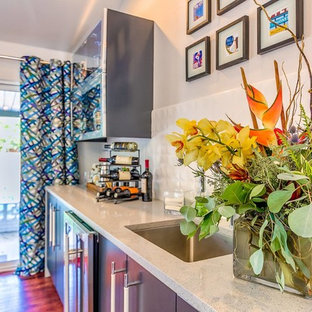 オクラホマシティの中サイズのコンテンポラリースタイルのおしゃれなウェットバー (アンダーカウンターシンク、フラットパネル扉のキャビネット、グレーのキャビネット、テラゾーカウンター、白いキッチンパネル、磁器タイルのキッチンパネル、濃色無垢フローリング、茶色い床) の写真