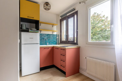 Cette image montre une petite cuisine américaine bicolore méditerranéenne en L avec un évier 1 bac, un plan de travail en bois, une crédence verte, une crédence en céramique, un électroménager blanc, un sol en travertin, un sol beige et un plan de travail beige.