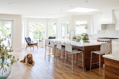 Example of a transitional light wood floor and brown floor kitchen design in Vancouver with an undermount sink, flat-panel cabinets, medium tone wood cabinets, quartz countertops, white backsplash, stone slab backsplash, stainless steel appliances and two islands