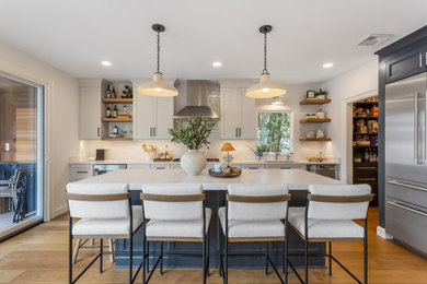 Inspiration for a large transitional medium tone wood floor and brown floor kitchen remodel in New York with an undermount sink, white backsplash, stainless steel appliances, an island, recessed-panel cabinets, beige cabinets and white countertops