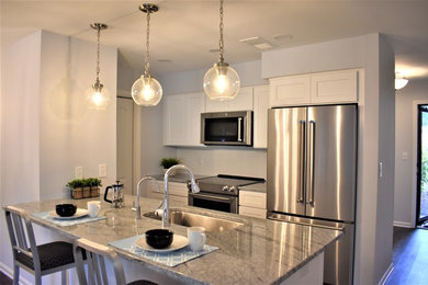Eat-in kitchen - mid-sized transitional galley brown floor eat-in kitchen idea in Charlotte with an undermount sink, recessed-panel cabinets, white cabinets, granite countertops, white backsplash, subway tile backsplash, stainless steel appliances, a peninsula and gray countertops
