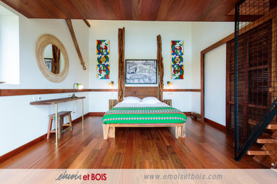 Diseño de dormitorio principal exótico de tamaño medio con paredes blancas y suelo de madera en tonos medios