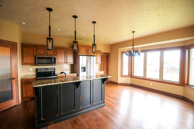 Elegant galley medium tone wood floor eat-in kitchen photo in Other with a double-bowl sink, distressed cabinets, granite countertops, beige backsplash, ceramic backsplash, stainless steel appliances and an island