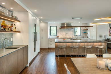 This is an example of a mid-sized contemporary l-shaped eat-in kitchen in Philadelphia with a single-bowl sink, flat-panel cabinets, white cabinets, quartz benchtops, white splashback, stone slab splashback, panelled appliances, light hardwood floors, with island and grey benchtop.