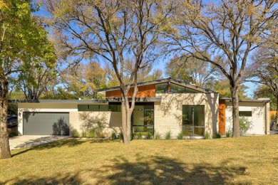 This is an example of a mid-sized midcentury one-storey white house exterior in Austin with stone veneer, a gable roof, a metal roof and a black roof.