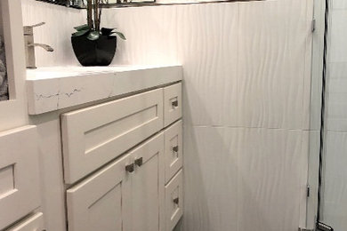 Example of a white tile and porcelain tile porcelain tile and gray floor corner shower design in San Francisco with white cabinets, white walls, marble countertops, a hinged shower door and white countertops