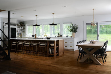 Farmhouse l-shaped medium tone wood floor and brown floor eat-in kitchen photo in Detroit with a farmhouse sink, shaker cabinets, white cabinets, stainless steel appliances, an island and white countertops