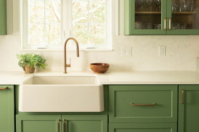 Large transitional l-shaped porcelain tile and gray floor kitchen photo in Portland Maine with a farmhouse sink, shaker cabinets, green cabinets, quartz countertops, white backsplash, quartz backsplash and white countertops