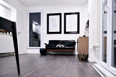 Immagine di un soggiorno minimalista stile loft con pareti bianche, pavimento in laminato, TV a parete e pavimento marrone